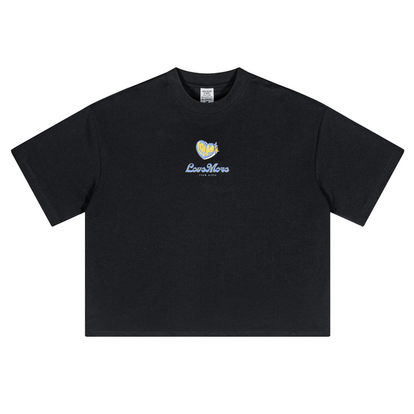 Black oversized cropped t-shirt by Love More Club featuring a yellow and blue heart logo with "LoveMore" text embroidered on the chest.