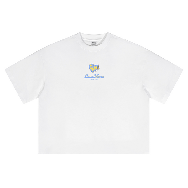 White oversized cropped t-shirt by Love More Club featuring a small yellow and blue heart logo with "LoveMore" text embroidered on the chest.